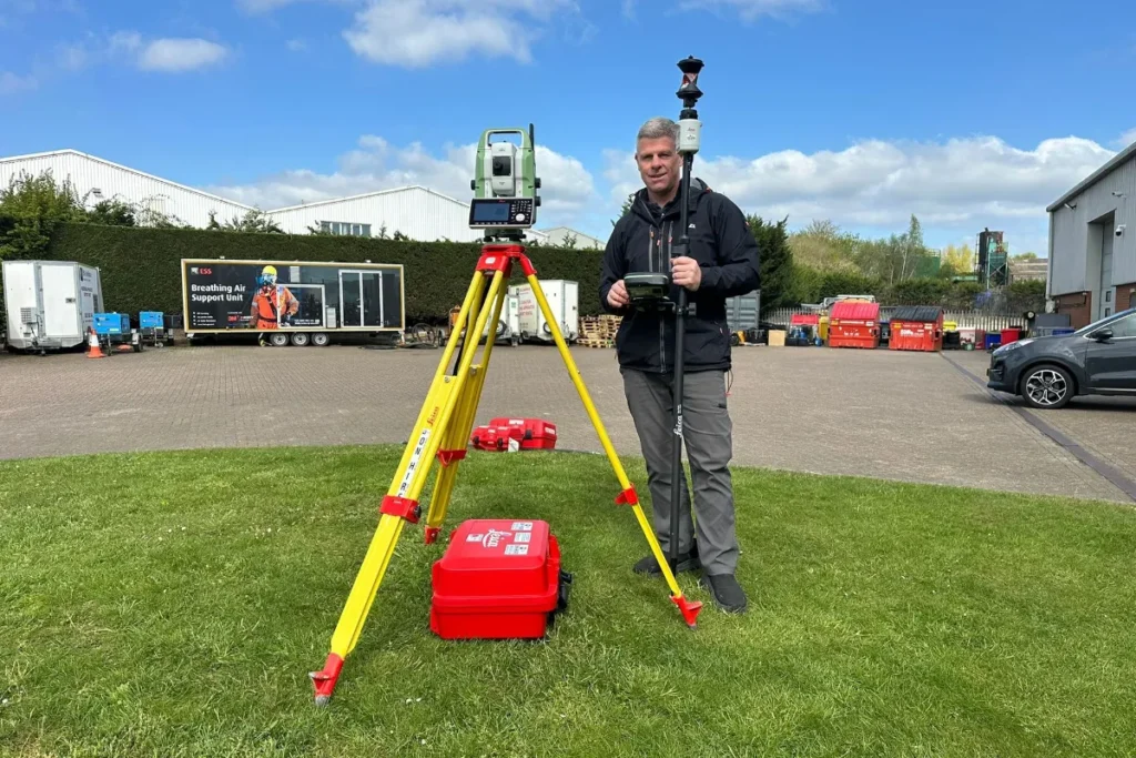 Land Surveyor Using Total Station and GPS Rover Equipment Surveyor setting up a total station on a tripod with a GPS rover pole in an outdoor industrial area