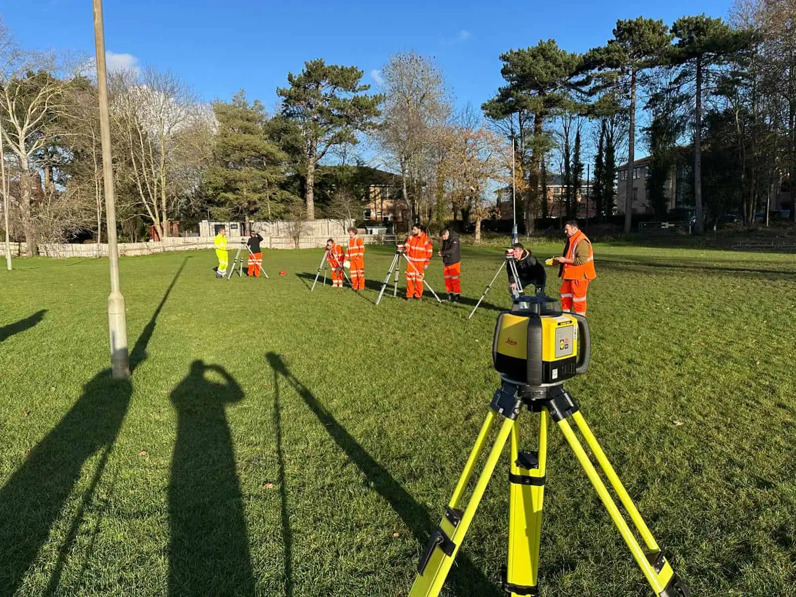 Students practising levelling and tape measurement during outdoor construction surveying training.