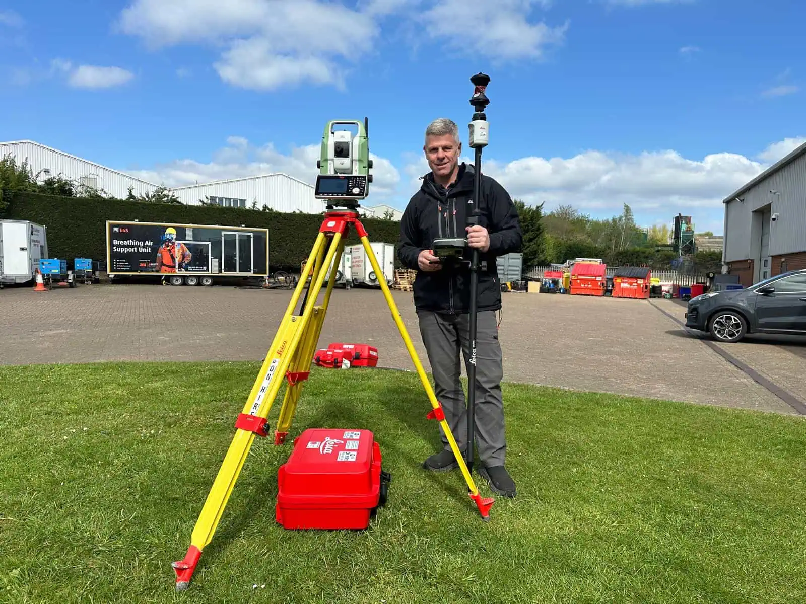 Instructor standing beside robotic total station equipment during practical training.